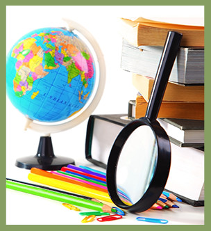 Stacked books, colored pencils, paperclips, a magnifying glass and a globe